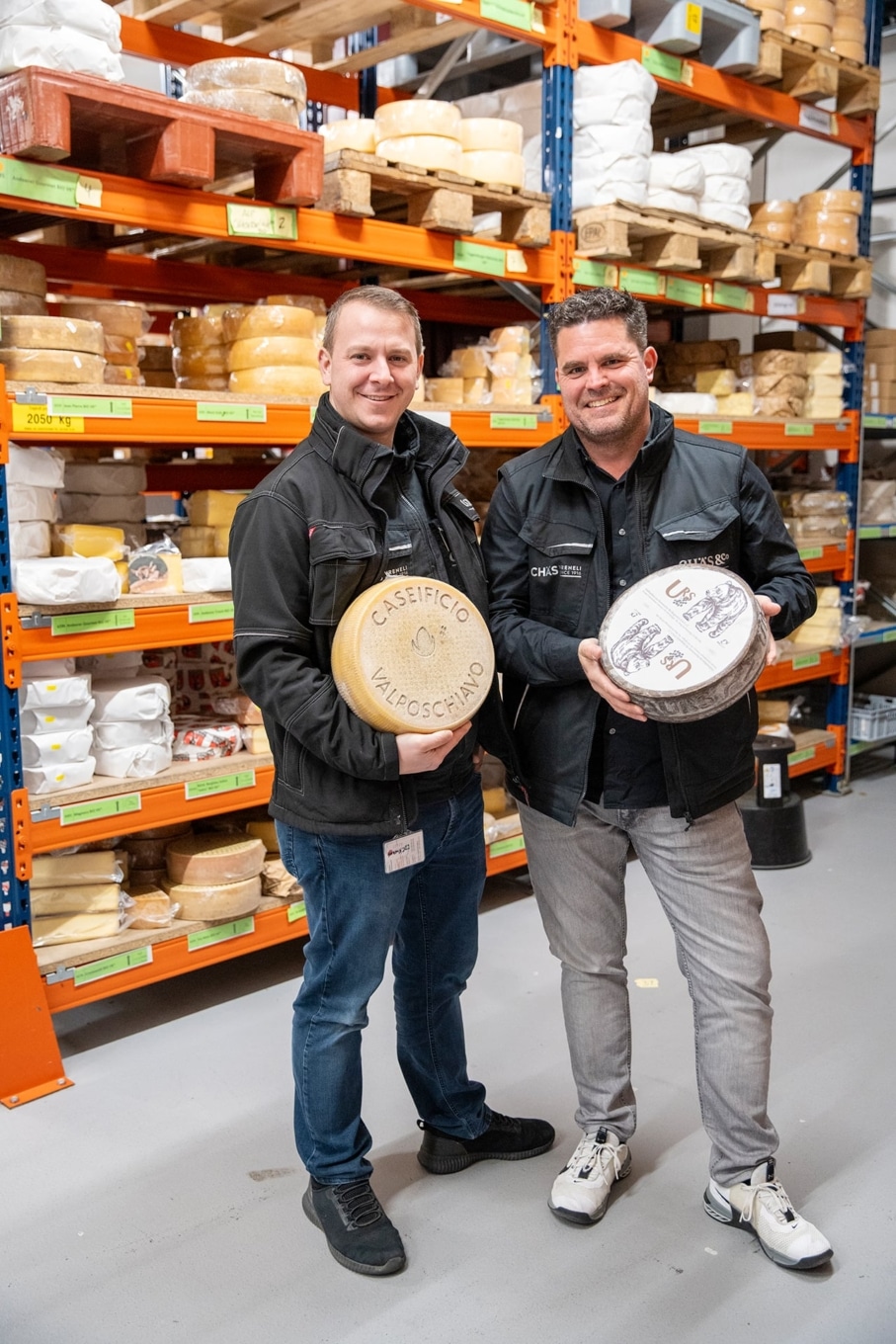 Christian Kuckert und Matthias Moser von Chäs & Co. halten Käselaibe im Lager